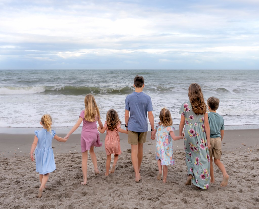 family photo of children walking towards ocean